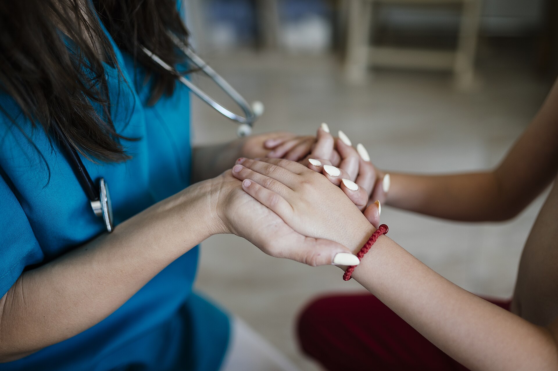 A clinician gently holding a patient’s hands in a supportive gesture